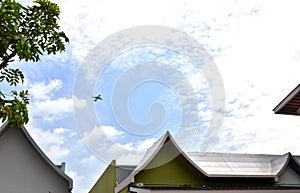 Airplane above tree and house