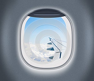 Airplane or aeroplane window with wing and cloudy sky behind