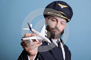 Airplane aviator in aircrew uniform looking at plane model,