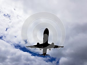 Airplane belly before landing on a blue sky background