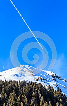 Airplane in a blue sky with traces. Mountain Hohe Salve