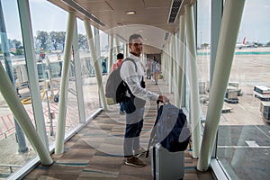 Airplane Boarding. Young male passenger carrying the hand luggage bag, walking the airplane boarding corridor.