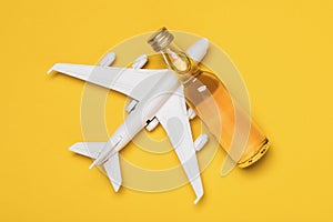 Airplane and bottle of whiskey on a yellow background, top view. Concept on the topic of drunkenness among pilots