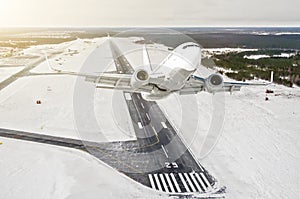 Airplane is climb flight level high view in the air, against the background of the winter airport of the runway, city, snow, fores