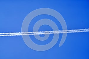 An airplane contrail in a clear blue sky.