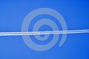 An airplane contrail in a clear blue sky.