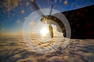 Airplane engine and propeller over clouds with sun and blue sky