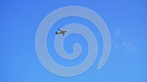 Airplane flies overhead through frame on clear, blue sky day. Slow motion passenger jet airline flying overhead on a beautiful cle