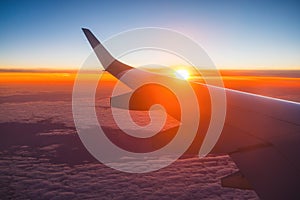 Airplane flight in sunset sky over ocean water and wing of plane. View from the window of the Aircraft. Traveling in air