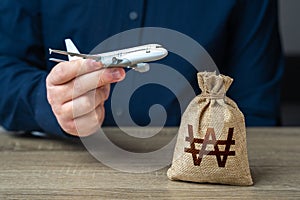 Airplane flights and South Korean won money bag. Airline industry income. Budget allocations