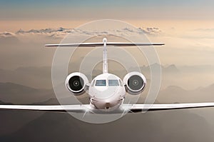 Airplane fly over clouds and Alps mountain on sunset. Front view of a big passenger or cargo aircraft, business jet