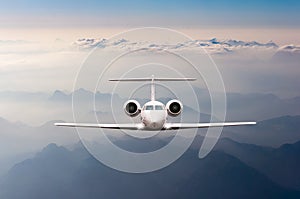 Airplane fly over clouds and Alps mountain on sunset. Front view of a big passenger or cargo aircraft, business jet