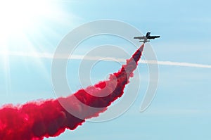 Airplane fly in zigzags with a red trail smoke in the sky.