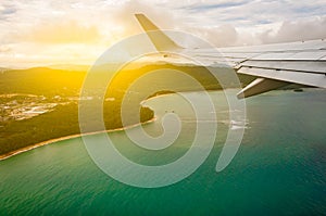 Airplane flying above beach blue sea island, taken from window w