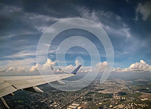 Airplane flying above clouds in aircraft wing on blue sky background