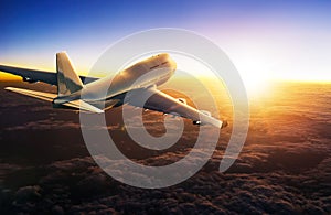 Airplane flying above clouds during sunset