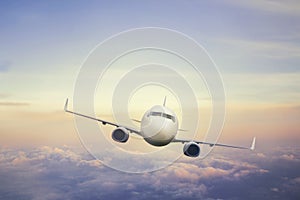 Airplane flying above clouds in sunset light