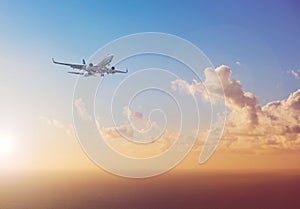 Airplane flying above ocean with sunset sky background - trav