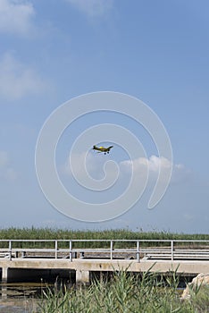 Airplane flying above a wheat field and blue sky with picturesque clouds