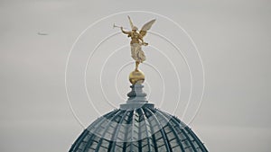 Airplane flying behind golden statue of Pheme or Fama on top of the glass dome of the Dresden Academy of Fine Arts photo