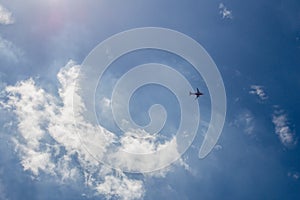 Airplane is flying in blue sky background with cloud and sunshine