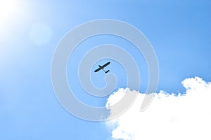 Airplane flying in the blue sky on background of white clouds, rear view. Twin-engine commercial plane during the turn, vacation