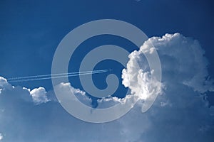 Airplane flying in the blue sky among clouds.