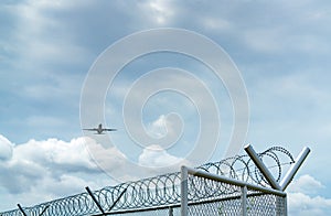 Airplane flying on blue sky and white clouds above metal fence. Aviation business. Commercial plane. Air transportation. Fence for