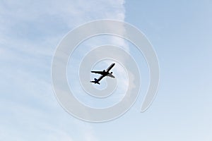 Airplane flying in a clear pale blue sky. Cloudy background