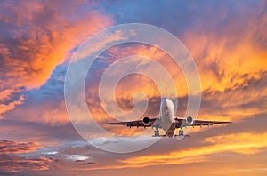 Airplane is flying in colorful sky at sunset. Passenger airplane