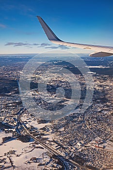 Airplane flying low over snowy mountains and preparing for landing to the airport, view from plane window of wing turbine and