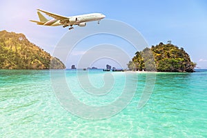 Airplane flying over above tropical island in the sea.