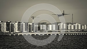 Airplane flying over buildings and water. Prepare for landing.