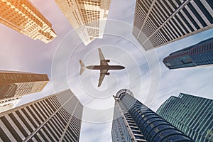 Airplane flying over city business buildings, high-rise skyscrapers