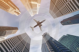 Airplane flying over city business buildings, high-rise skyscrapers