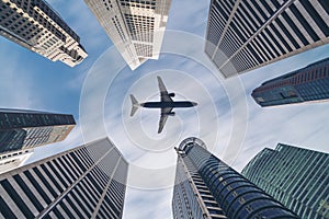 Airplane flying over city business buildings, high-rise skyscrapers