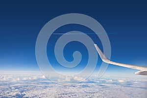 Airplane flying over color sky clouds during scenic sunset or sunrise cloudscape, view from plane window of wing turbines and