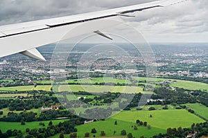 Airplane flying over green fields close London