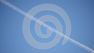 Airplane flying over leaving a thick condensation stripe behind on the sky