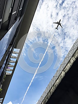 Airplane flying over between modern architecture and expressway.