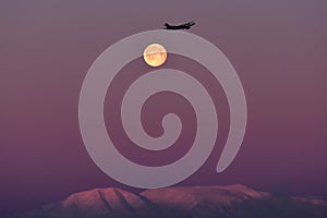 Airplane flying over moon and mountain