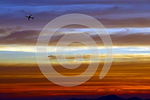 airplane flying over the rainbow and blue sky red orange yellow cloud in sunset