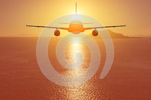 Airplane flying over the sea at sunset. Travel concept
