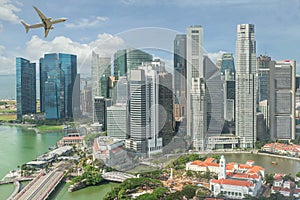 Airplane flying over Singapore business district in morning