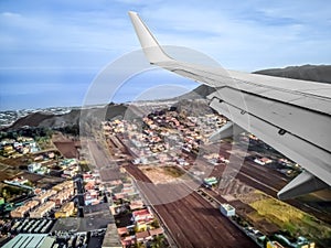 Airplane flying over the town and fields in Tenerife, Spain