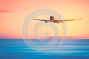 Airplane flying over tropical beach with smooth wave and sunset sky abstract background