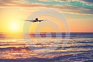 Airplane flying over tropical beach with smooth wave and sunset sky abstract background