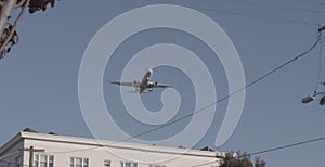 Airplane flying over white buildings under a gloomy grayish-blue sky on a windy day