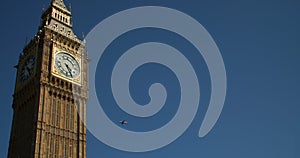 Airplane flying past Big Ben, Houses of Parliament in a blue sky, summer, London, England