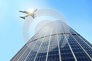 Airplane flying past a modern skyscraper,